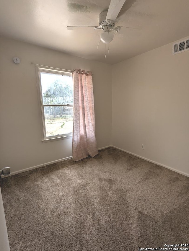 carpeted empty room featuring baseboards, visible vents, and a ceiling fan