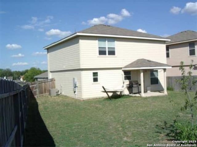 rear view of house featuring a lawn, a fenced backyard, cooling unit, and a patio area