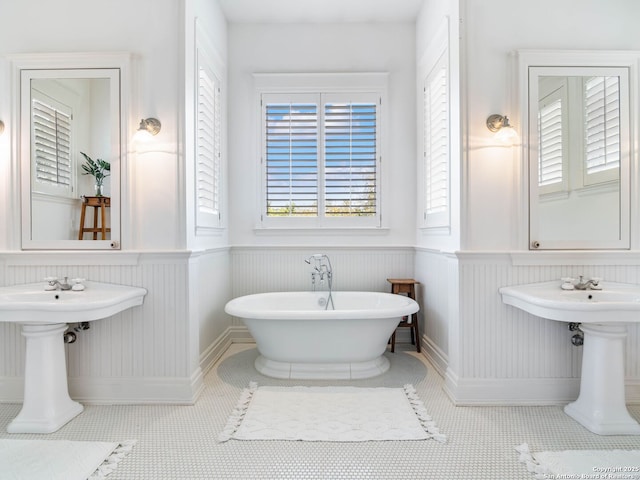 full bath with a sink, a freestanding tub, and a wainscoted wall