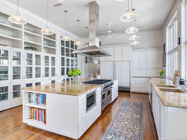 kitchen featuring open shelves, a ceiling fan, island range hood, a sink, and stainless steel appliances
