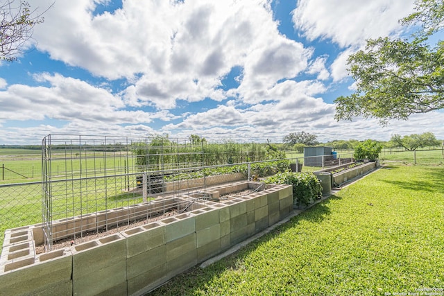 view of yard with an outbuilding, fence, a rural view, and a vegetable garden