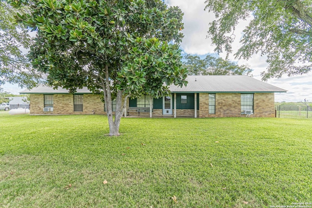 view of front facade featuring metal roof, fence, and a front lawn