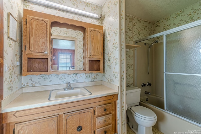 bathroom featuring a textured ceiling, wallpapered walls, shower / bath combination with glass door, and vanity