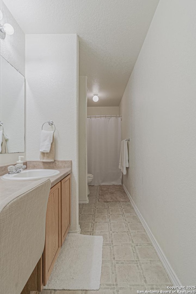 4907 Heather Pass, San Antonio, TX 78218 - full bathroom with vanity, toilet, baseboards, a textured ceiling, and tile patterned floors