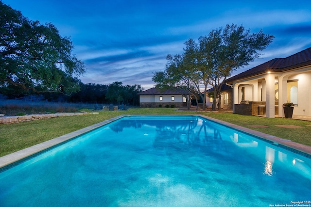 pool at dusk featuring a yard and an outdoor pool
