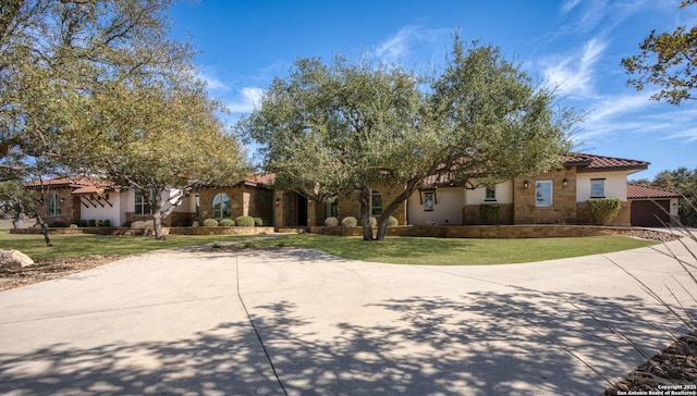 view of front of home with a front lawn, a tile roof, stucco siding, and driveway