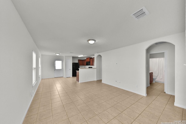 12266 Stratsburg, San Antonio, TX 78252 - unfurnished living room with light tile patterned flooring, arched walkways, baseboards, and visible vents