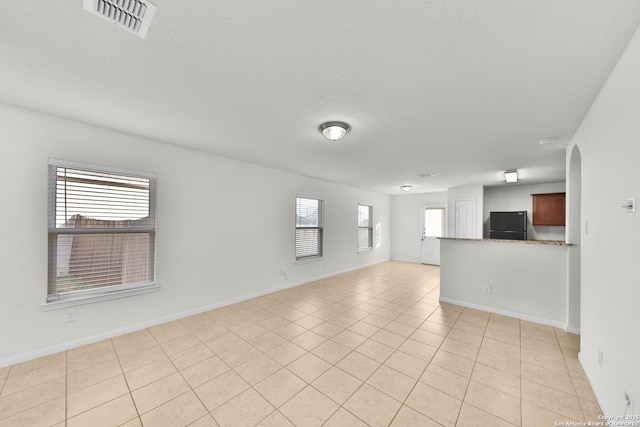 12266 Stratsburg, San Antonio, TX 78252 - spare room featuring arched walkways, baseboards, a textured ceiling, and visible vents