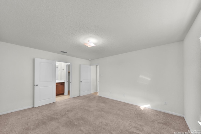 12266 Stratsburg, San Antonio, TX 78252 - unfurnished bedroom featuring a textured ceiling, ensuite bath, light colored carpet, and visible vents