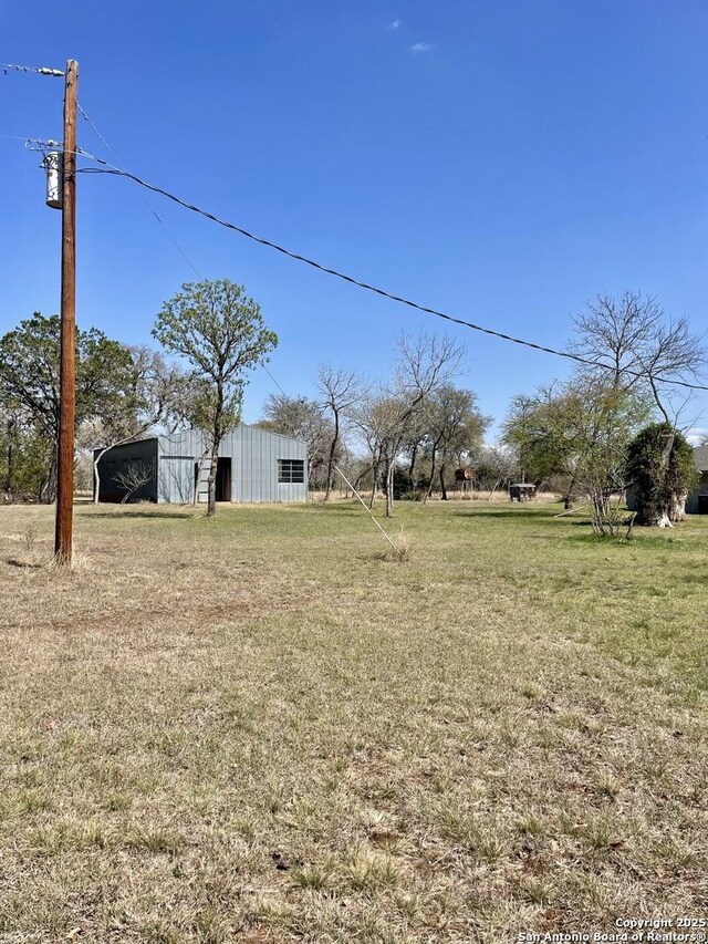 view of yard featuring an outdoor structure, a carport, and an outbuilding