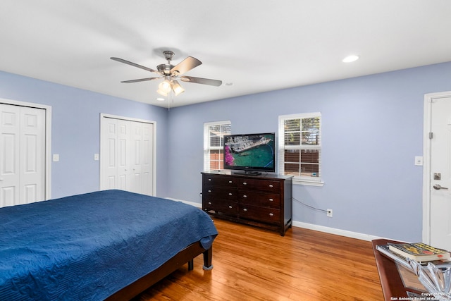 bedroom with a ceiling fan, wood finished floors, baseboards, two closets, and recessed lighting