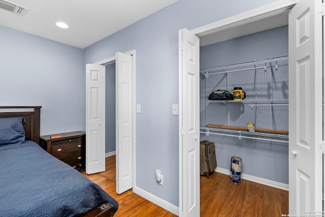bedroom with baseboards, visible vents, and wood finished floors
