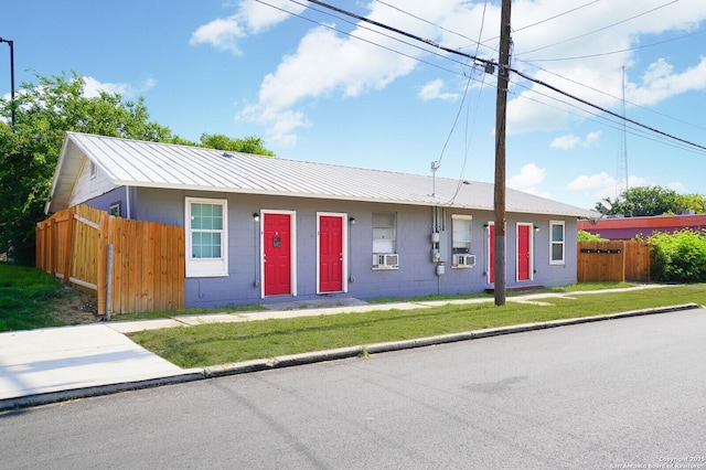 single story home featuring concrete block siding, a front yard, fence, and metal roof