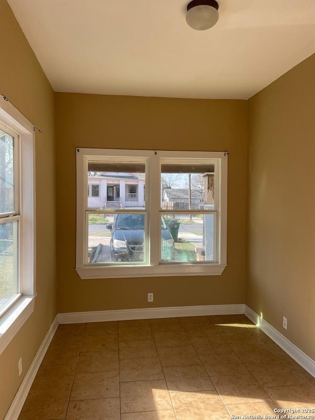 tiled empty room featuring baseboards