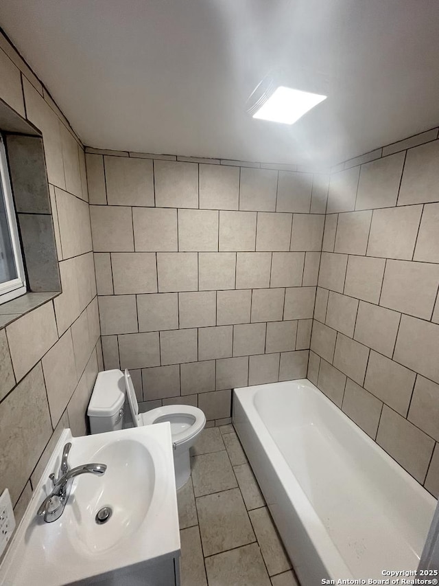 bathroom featuring tile patterned flooring, vanity, tile walls, a tub, and toilet
