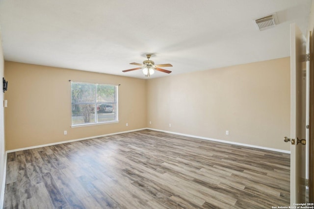 spare room with wood finished floors, visible vents, baseboards, and ceiling fan