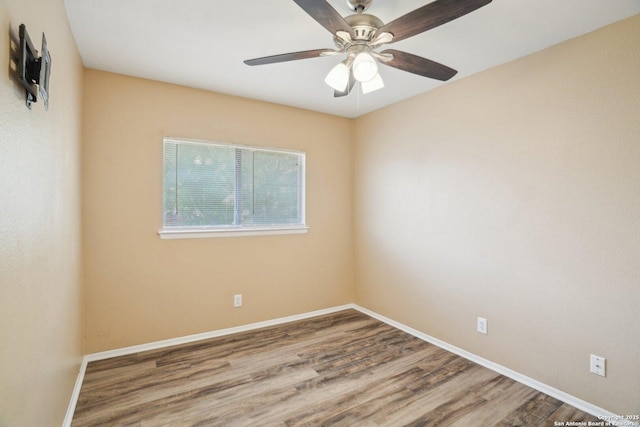 spare room featuring baseboards, wood finished floors, and a ceiling fan