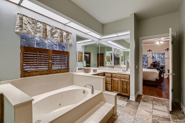 409 Sandy Oaks, Boerne, TX 78015 - bathroom featuring ensuite bathroom, stone finish flooring, ceiling fan, vanity, and a whirlpool tub