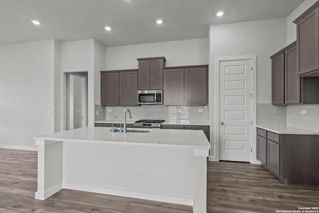 1509 Passmore Downs, New Braunfels, TX 78130 - kitchen featuring appliances with stainless steel finishes, a sink, a center island with sink, dark wood-style floors, and decorative backsplash