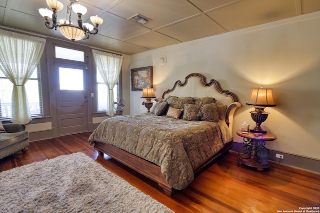 bedroom featuring wood finished floors, visible vents, and a chandelier