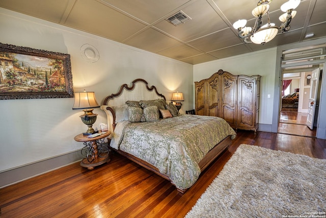 bedroom featuring baseboards, wood finished floors, a chandelier, and visible vents