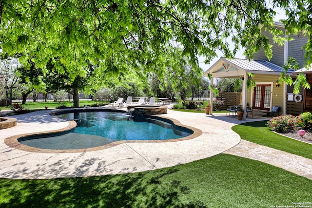 view of swimming pool featuring french doors, a yard, a pool with connected hot tub, and a patio