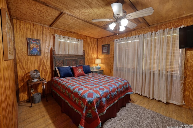 bedroom featuring wooden walls, wood finished floors, wood ceiling, and ceiling fan