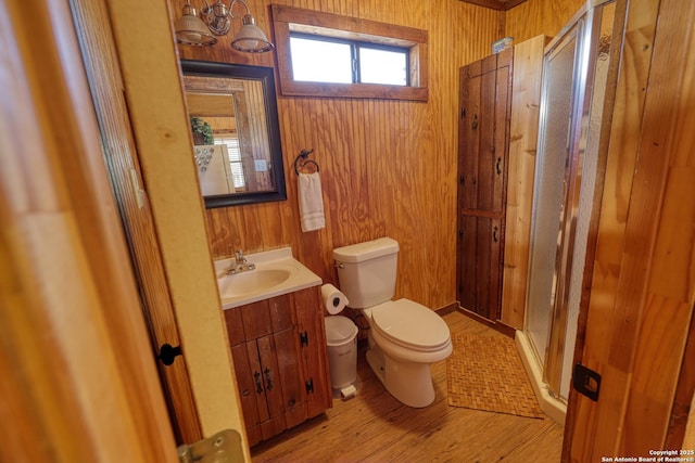 full bathroom featuring toilet, wood walls, vanity, and a stall shower