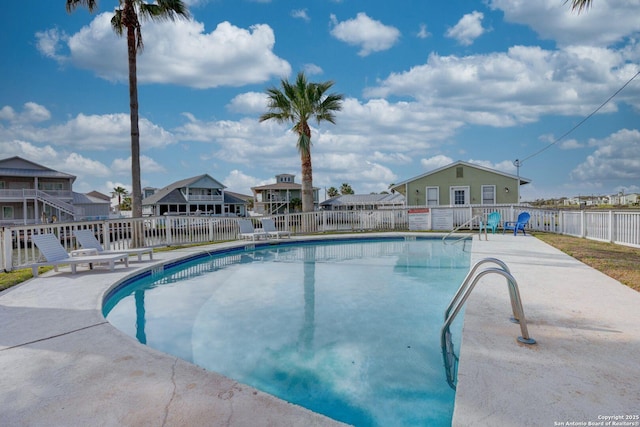 community pool featuring a residential view, fence, and a patio
