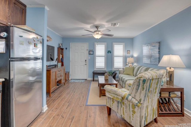 living area with crown molding, a ceiling fan, baseboards, visible vents, and light wood-style floors