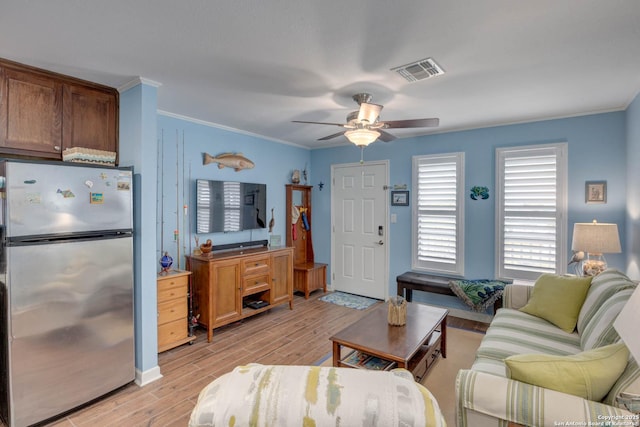 living area with light wood-style flooring, ceiling fan, visible vents, and crown molding