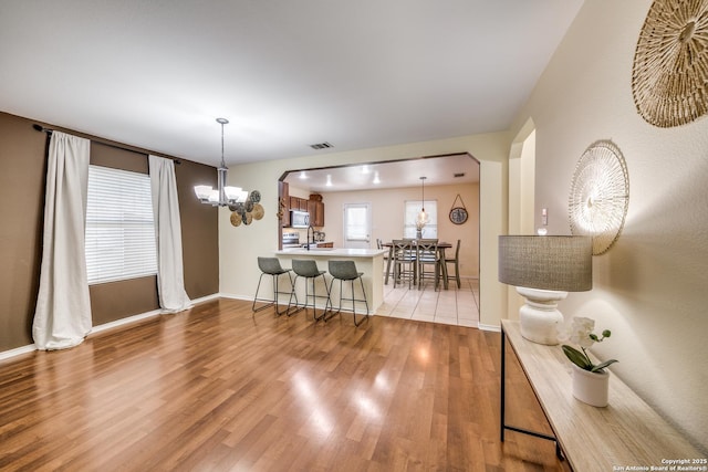 dining room featuring a notable chandelier, wood finished floors, baseboards, visible vents, and arched walkways