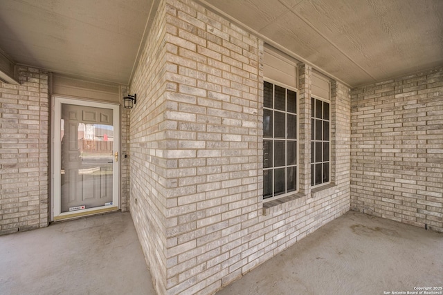 doorway to property with brick siding and covered porch