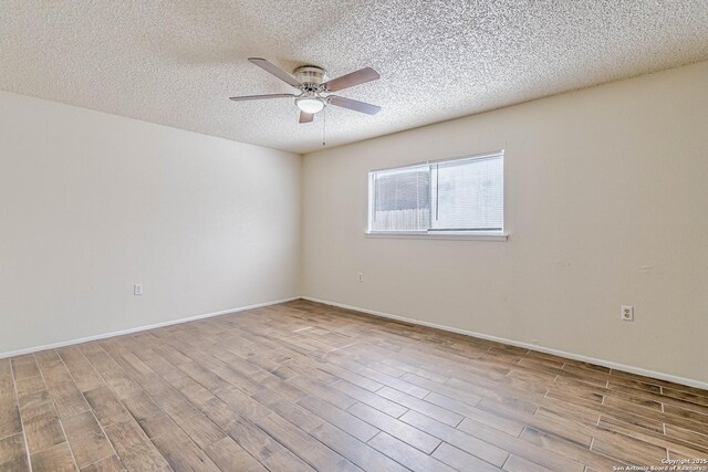 spare room featuring wood finished floors, a textured ceiling, baseboards, and ceiling fan