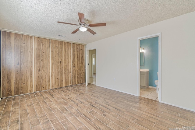 empty room with baseboards, a textured ceiling, light wood-style floors, visible vents, and ceiling fan