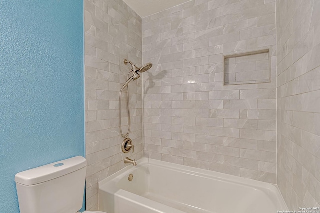 full bath with a textured wall, toilet, and shower / bath combination