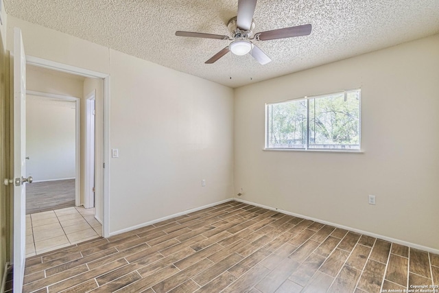 unfurnished room featuring a textured ceiling, baseboards, ceiling fan, and wood tiled floor