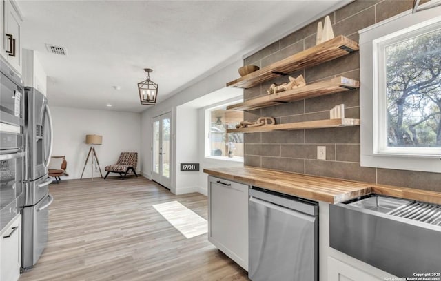 kitchen with tasteful backsplash, wooden counters, light wood-type flooring, visible vents, and white cabinets