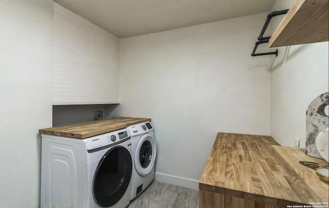 clothes washing area with baseboards, independent washer and dryer, laundry area, and light wood finished floors