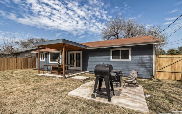 rear view of house with french doors, a fenced backyard, a lawn, and a patio