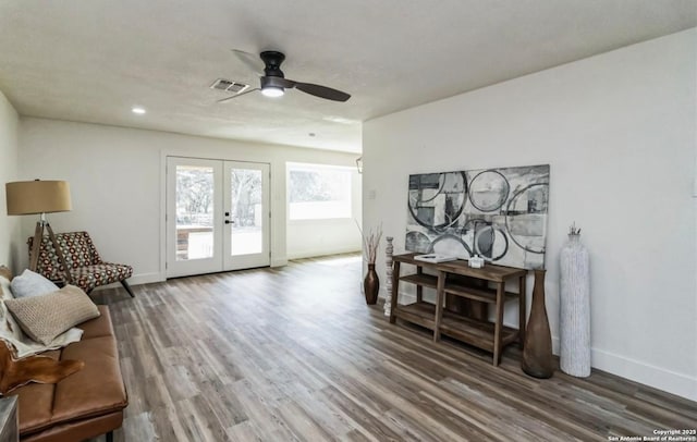 living area featuring visible vents, baseboards, wood finished floors, a ceiling fan, and french doors