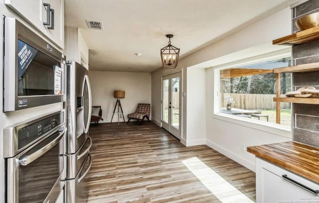 kitchen with a wealth of natural light, visible vents, white cabinets, and appliances with stainless steel finishes