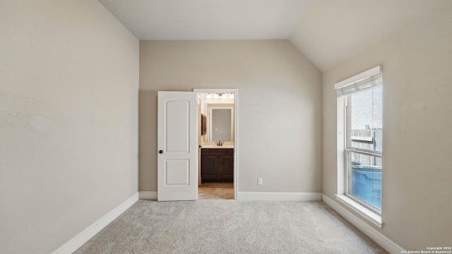2144 Pioneer Pass, Seguin, TX 78155 - unfurnished bedroom with light colored carpet, baseboards, a sink, lofted ceiling, and ensuite bathroom