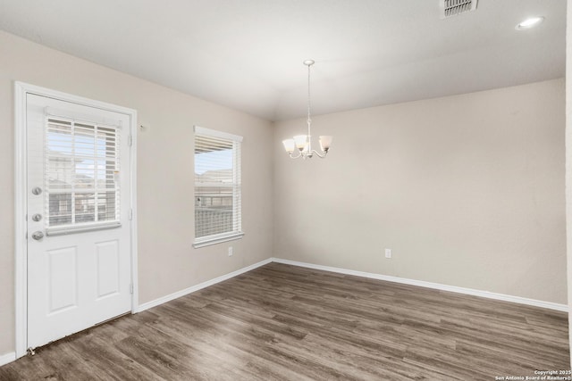 unfurnished dining area with baseboards, visible vents, a notable chandelier, and wood finished floors