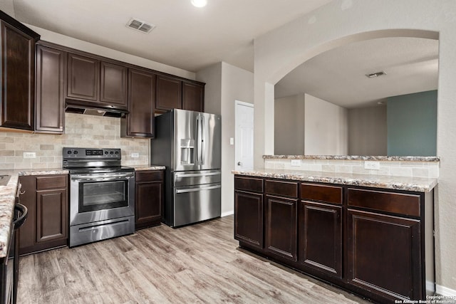 kitchen featuring arched walkways, stainless steel appliances, under cabinet range hood, and visible vents