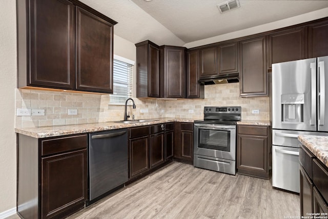 kitchen featuring visible vents, stainless steel appliances, under cabinet range hood, a sink, and light wood-style floors