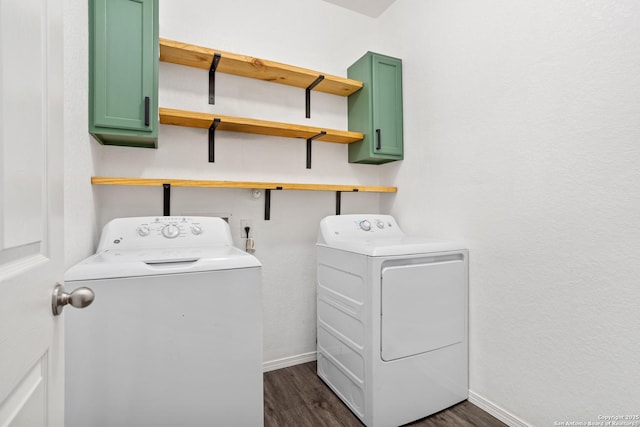 clothes washing area with dark wood-style floors, washing machine and dryer, cabinet space, and baseboards