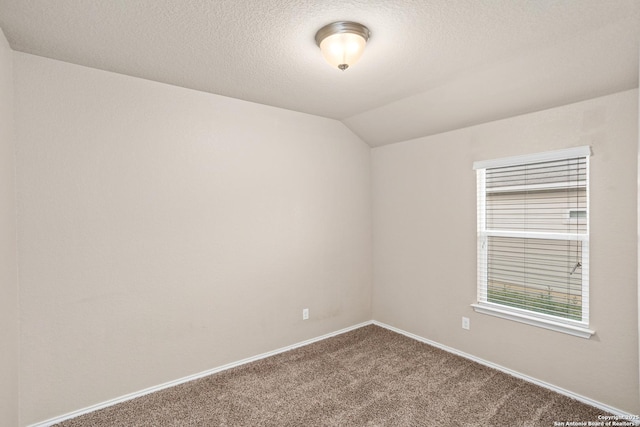 carpeted empty room featuring baseboards, vaulted ceiling, and a textured ceiling