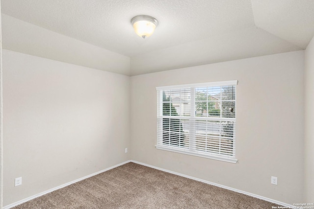 carpeted empty room with baseboards, vaulted ceiling, and a textured ceiling
