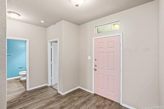 entryway with baseboards, wood finished floors, and a textured ceiling